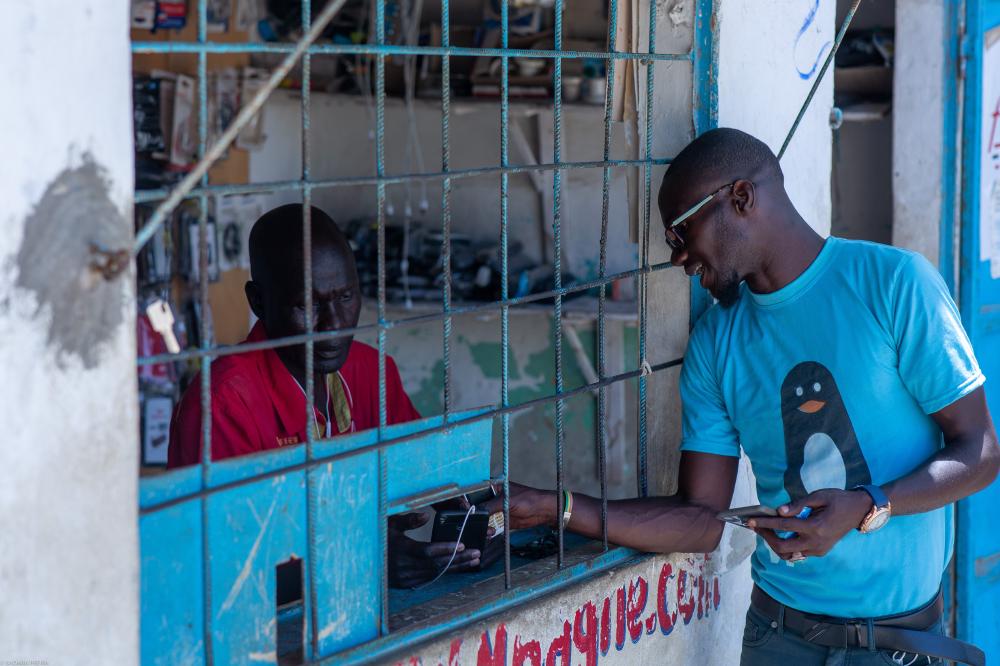 A man peering into a Wave agent kiosk covered in Wave stickers